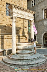 Me, peering down the ancient well in Piazza Pio II