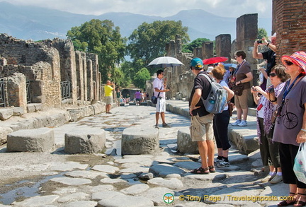 People cross the street on the high stone blocks avoiding any water and waste