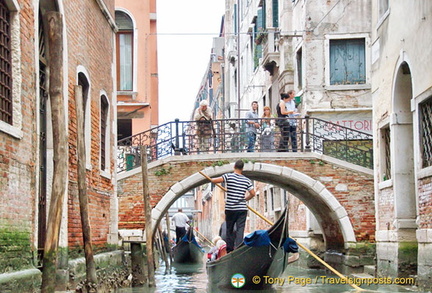 People on the bridge enjoying the flottila of gondolas cuising by