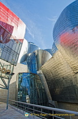 Guggenheim Bilbao's Titanium catches the red and blue of nearby structures